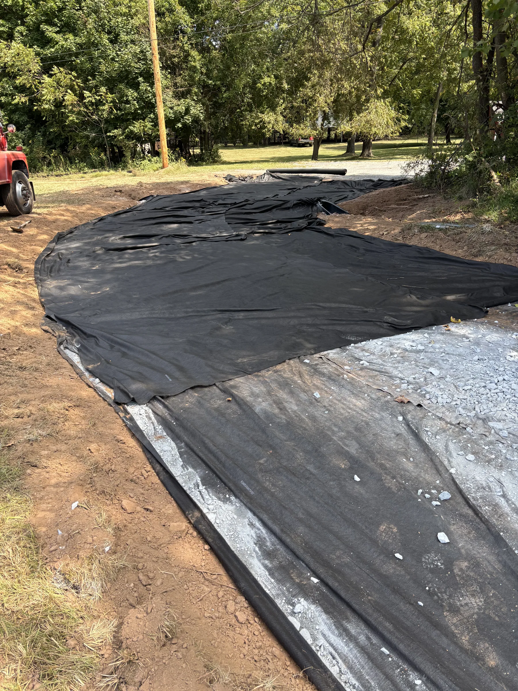 Black geotextile fabric being laid across a prepared septic field excavation in York County, PA