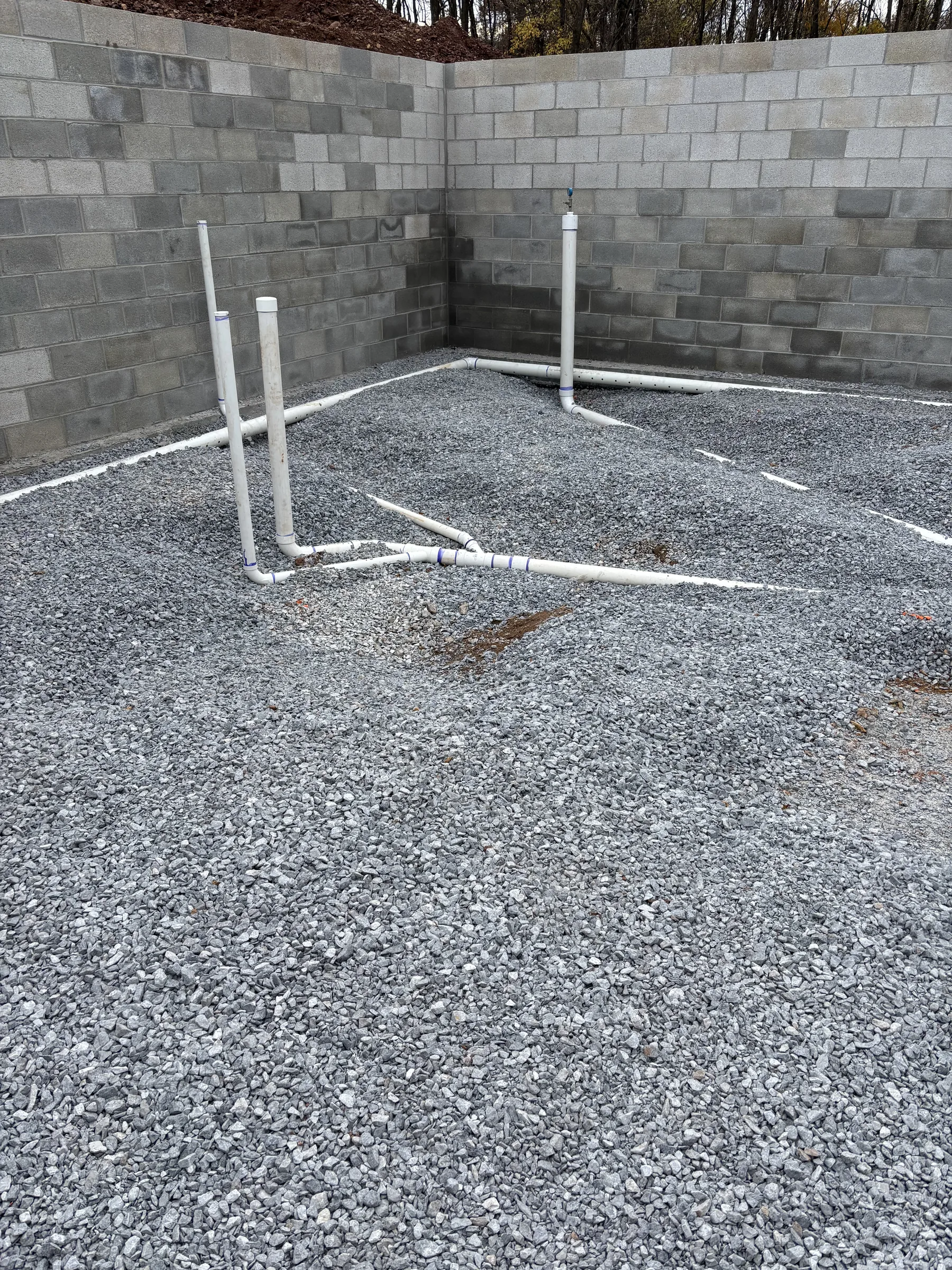 Foundation excavation with concrete footers and PVC plumbing roughed in at a residential project