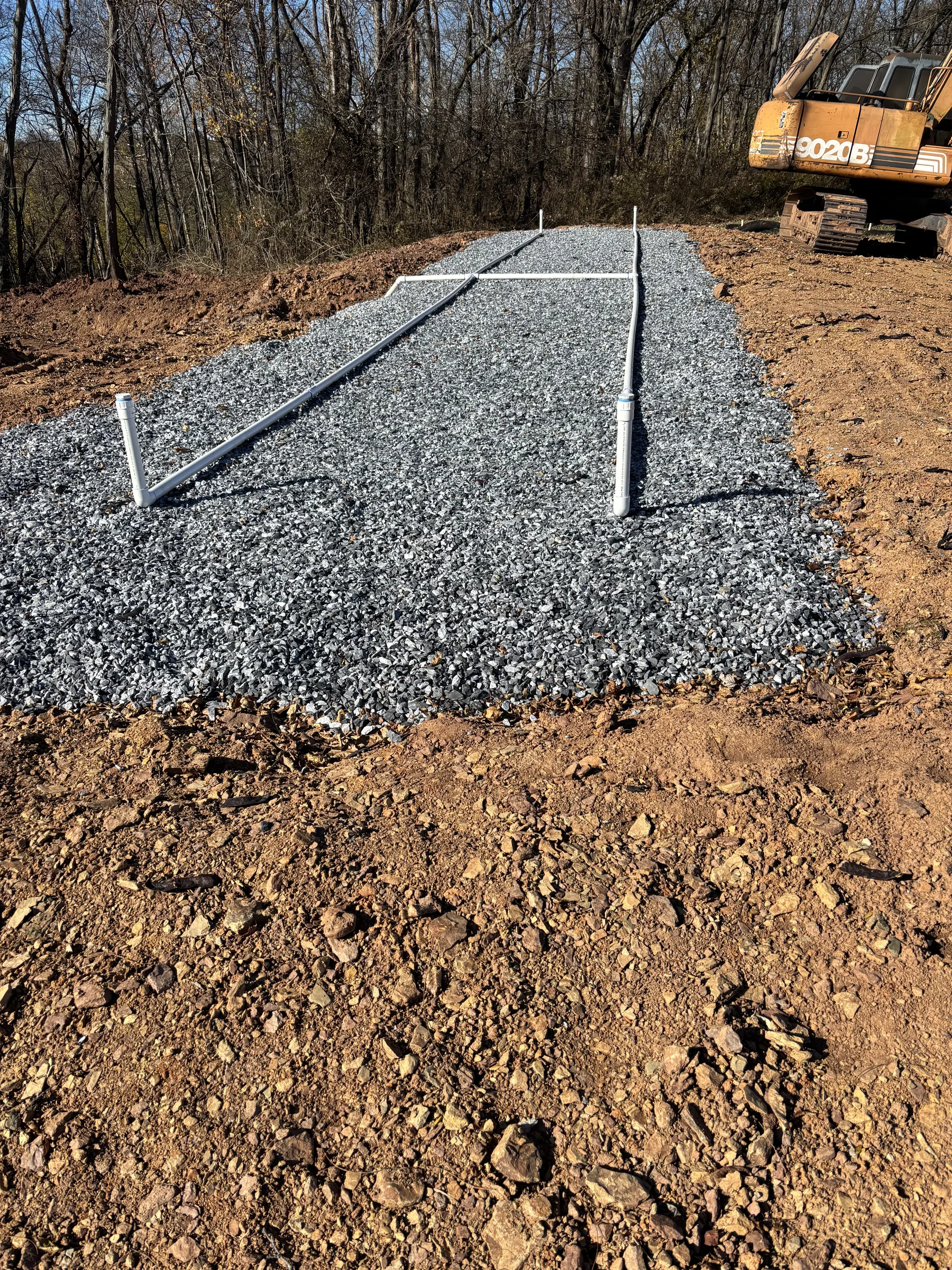Gravel driveway in progress with utility markers and equipment staged on site