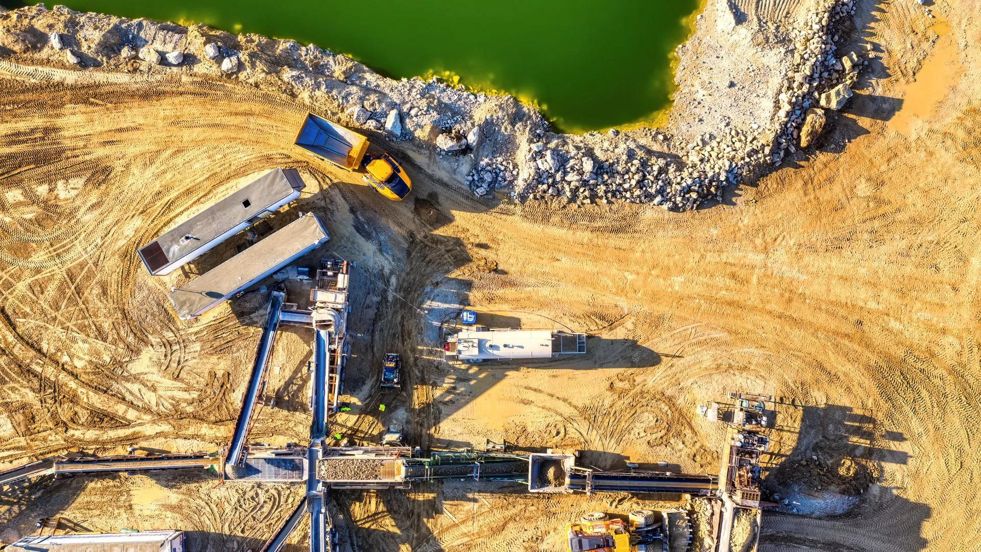 Aerial view of an excavation site with cleared gravel pad and staged equipment